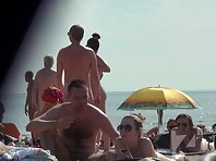 Nu1333# Naked men and women sunbathing on a nudist beach. In the frame gets a beautiful naked girl