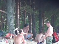 Nu1385# Nudist group took refuge from the sun in the shade of trees. They talk, have a drink and d