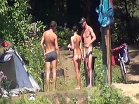 Nu1253# Company of two guys and a girl sunbathe and drink beer by the river. They have a fun. They